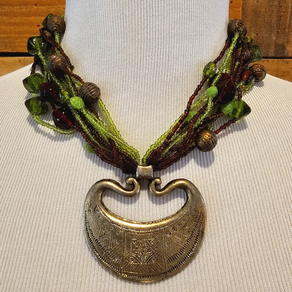 Green & brown multi-strand beaded necklace w. large goldtone tribal pendant